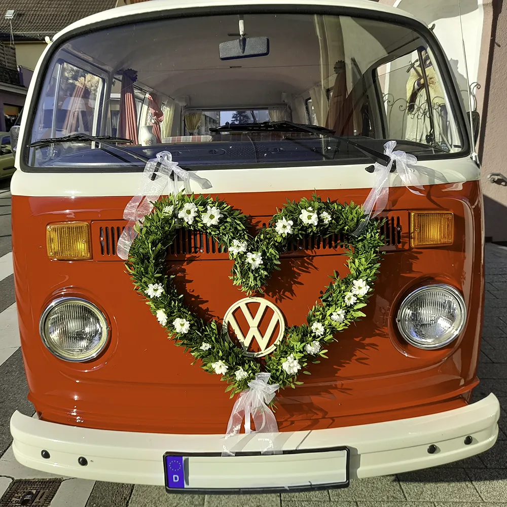 Blumengesteck in Herzform an einem roten Auto